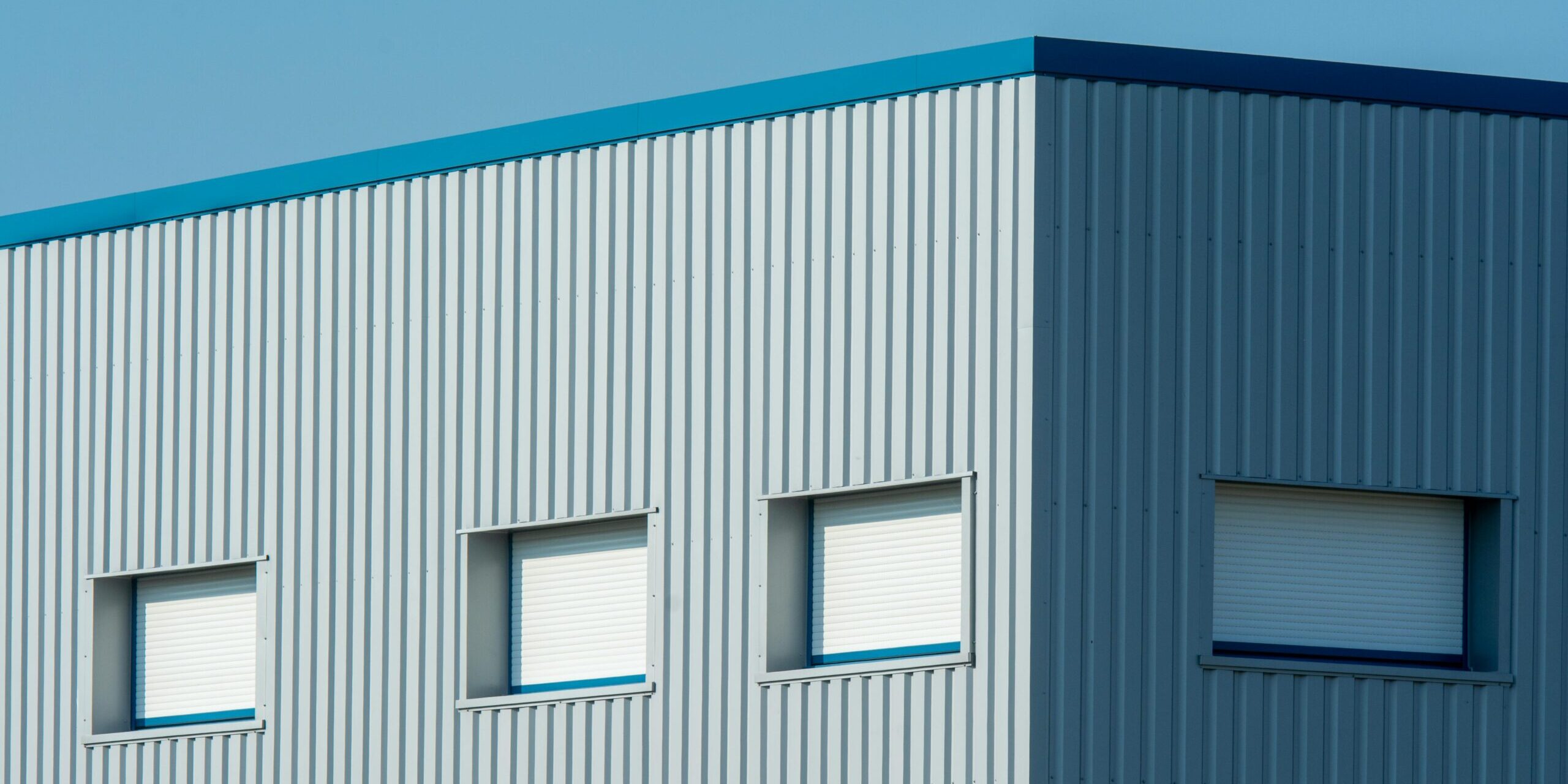A sleek industrial building with a corrugated meta A sleek industrial building with a corrugated metal facade featuring roller blinds and sandwich panels.