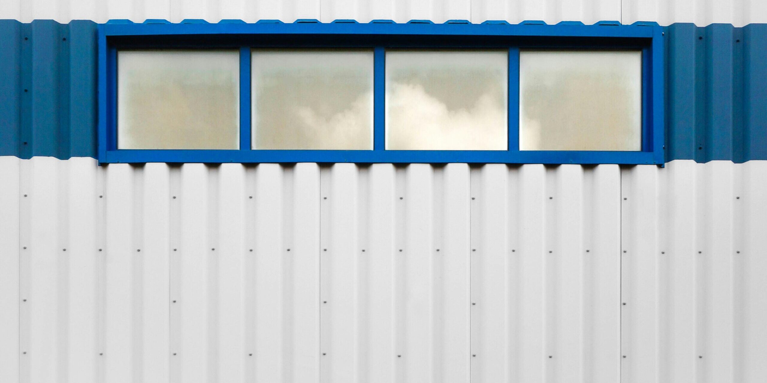 a white building with a blue window on the side of a white building with a blue window on the side of it