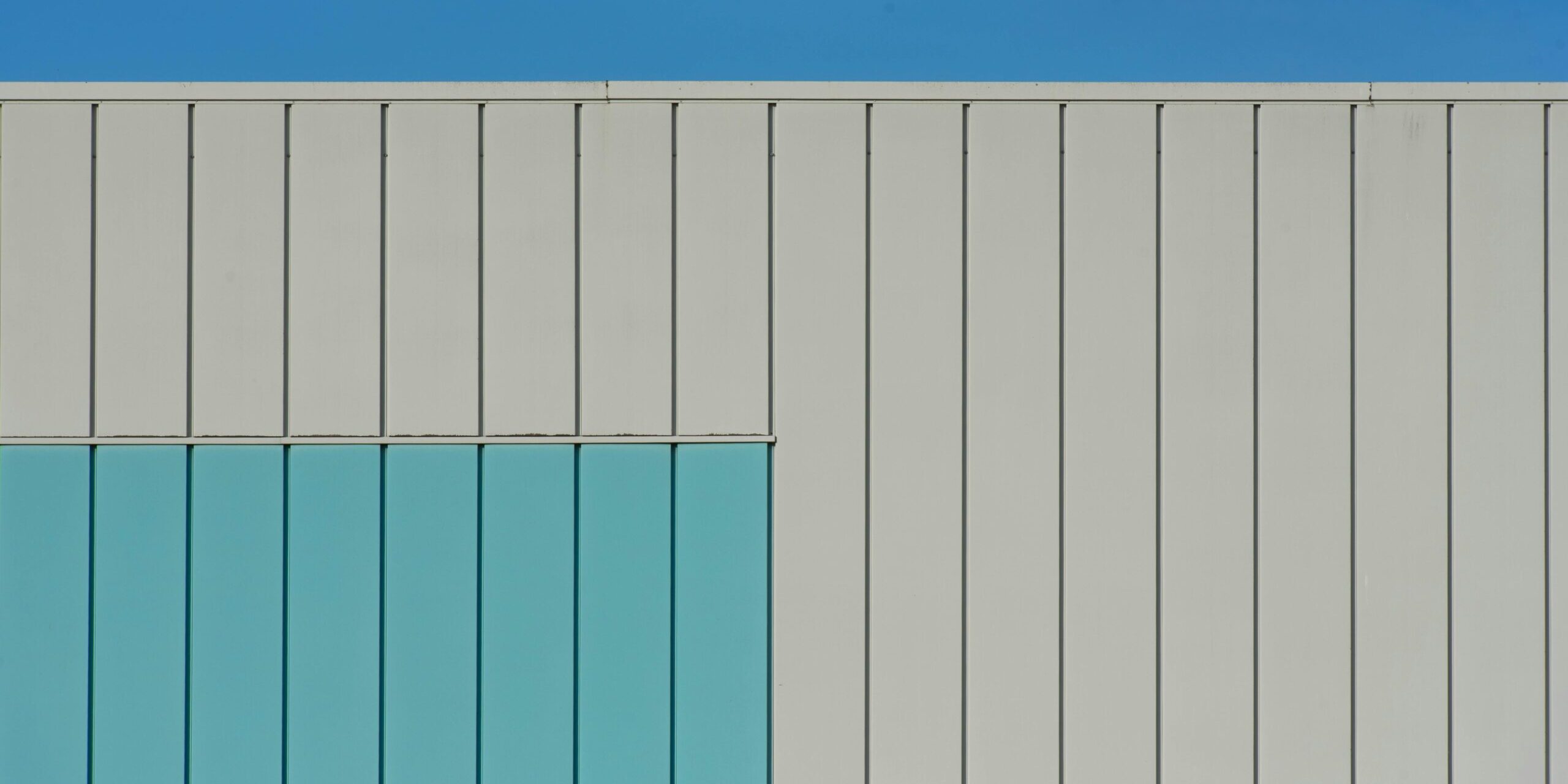 Abstract view of a modern building facade with geo Abstract view of a modern building facade with geometric design and blue accents under a clear sky.