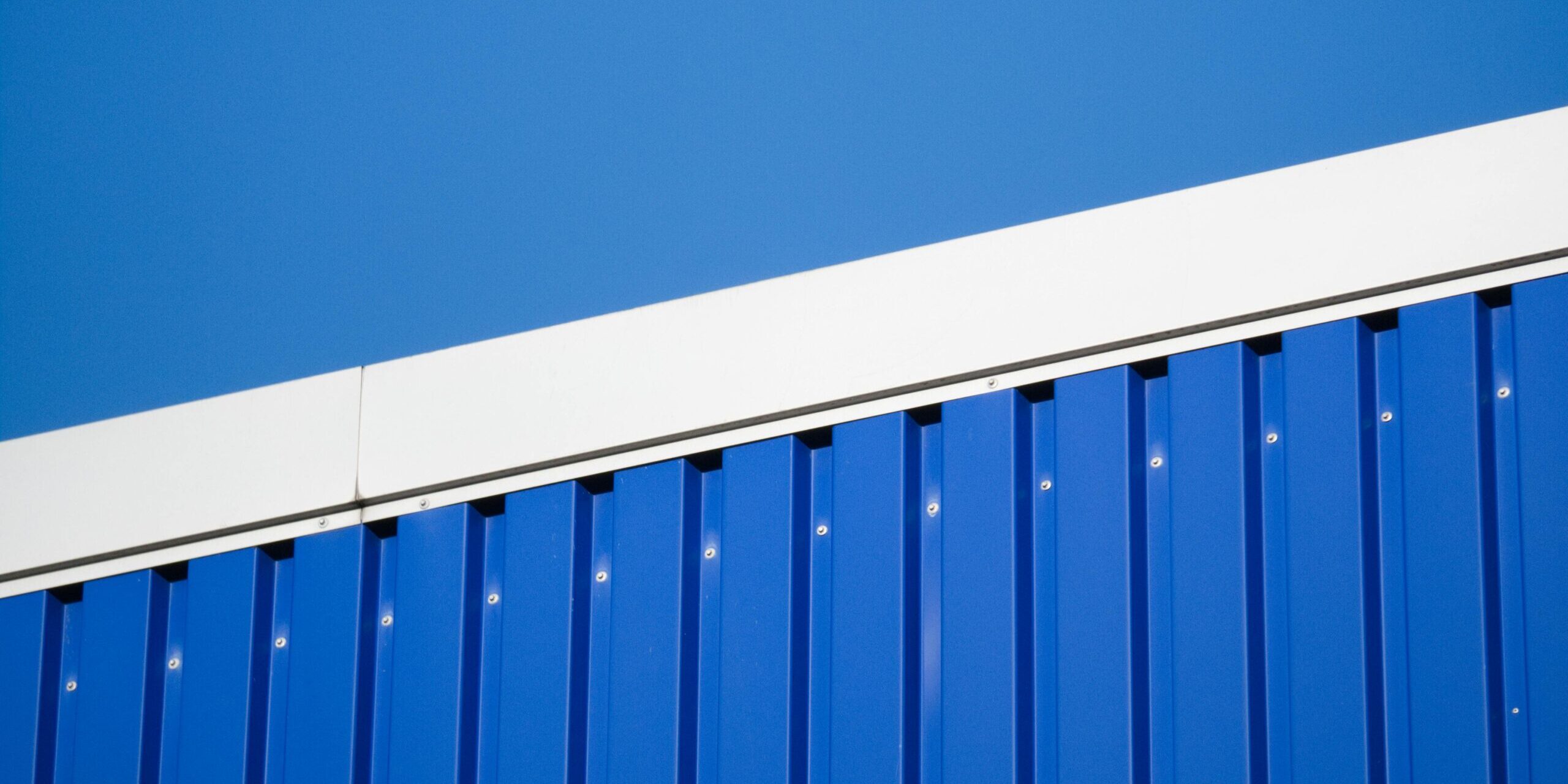 Close-up of a blue metal industrial wall against a clear sky in Hamburg.