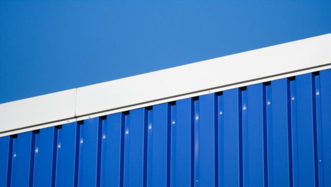 Close-up of a blue metal industrial wall against a clear sky in Hamburg.
