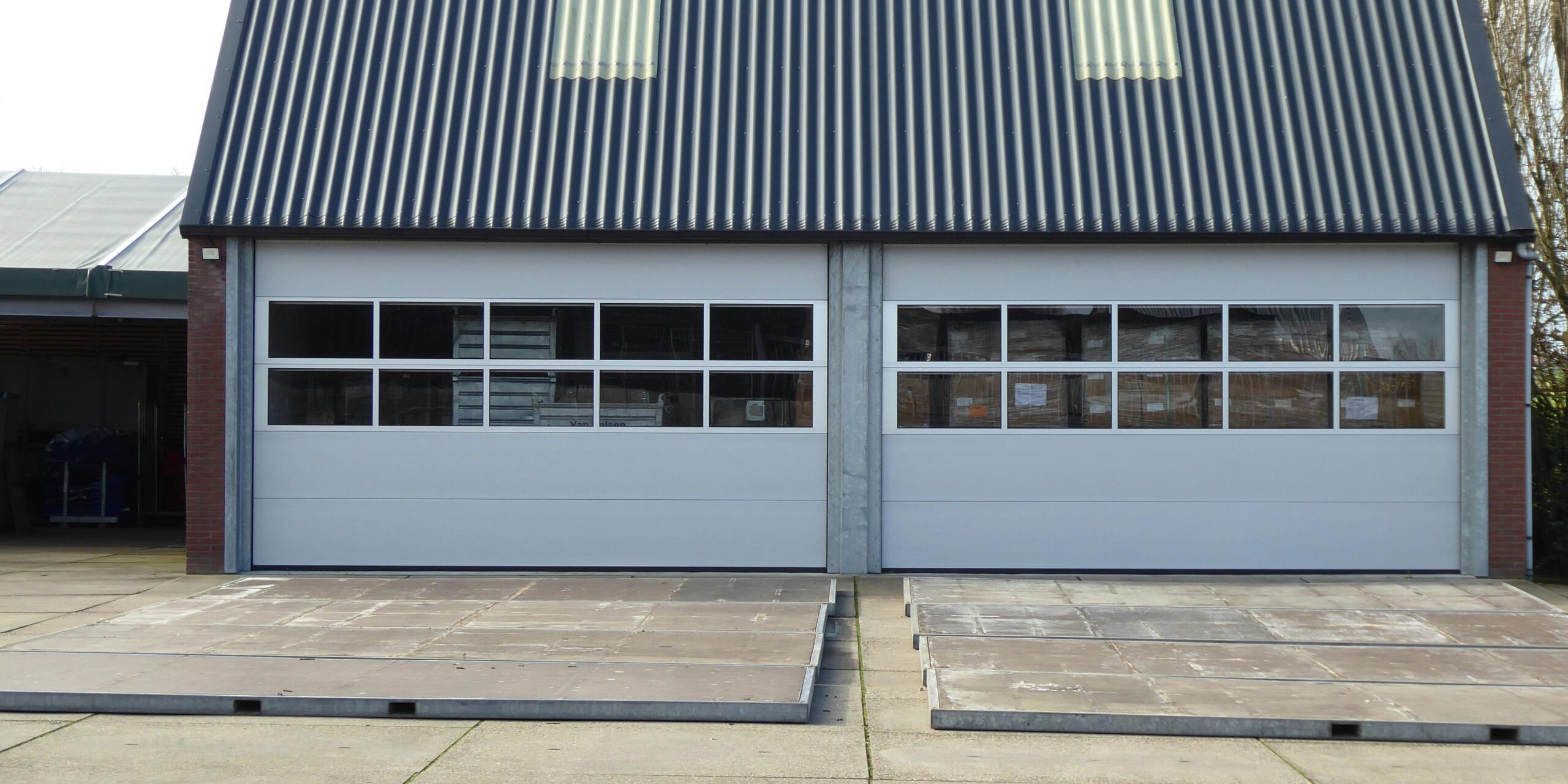 Front view of a modern warehouse building with cor Front view of a modern warehouse building with corrugated roofing and skylights.