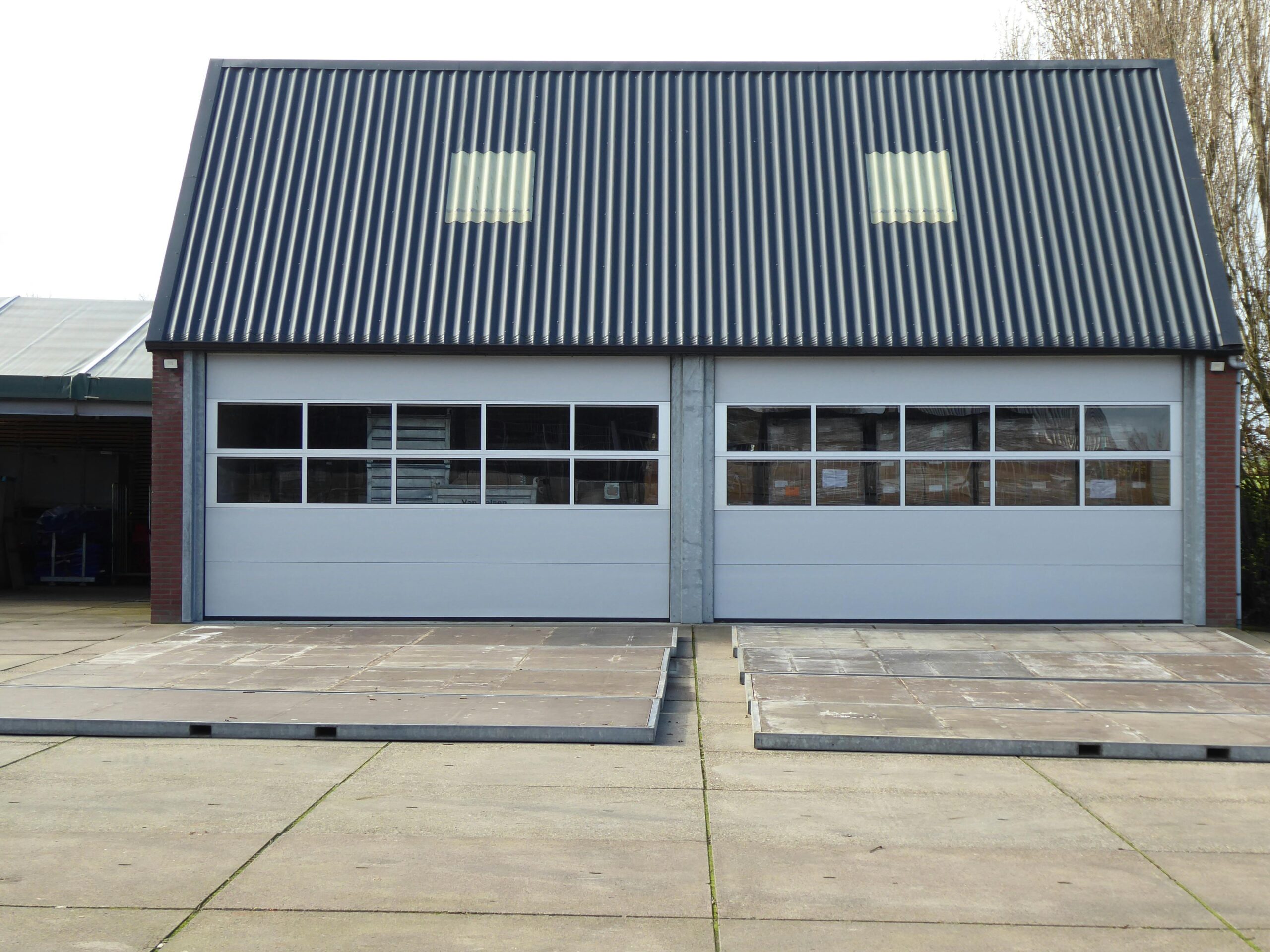 Front view of a modern warehouse building with corrugated roofing and skylights.
