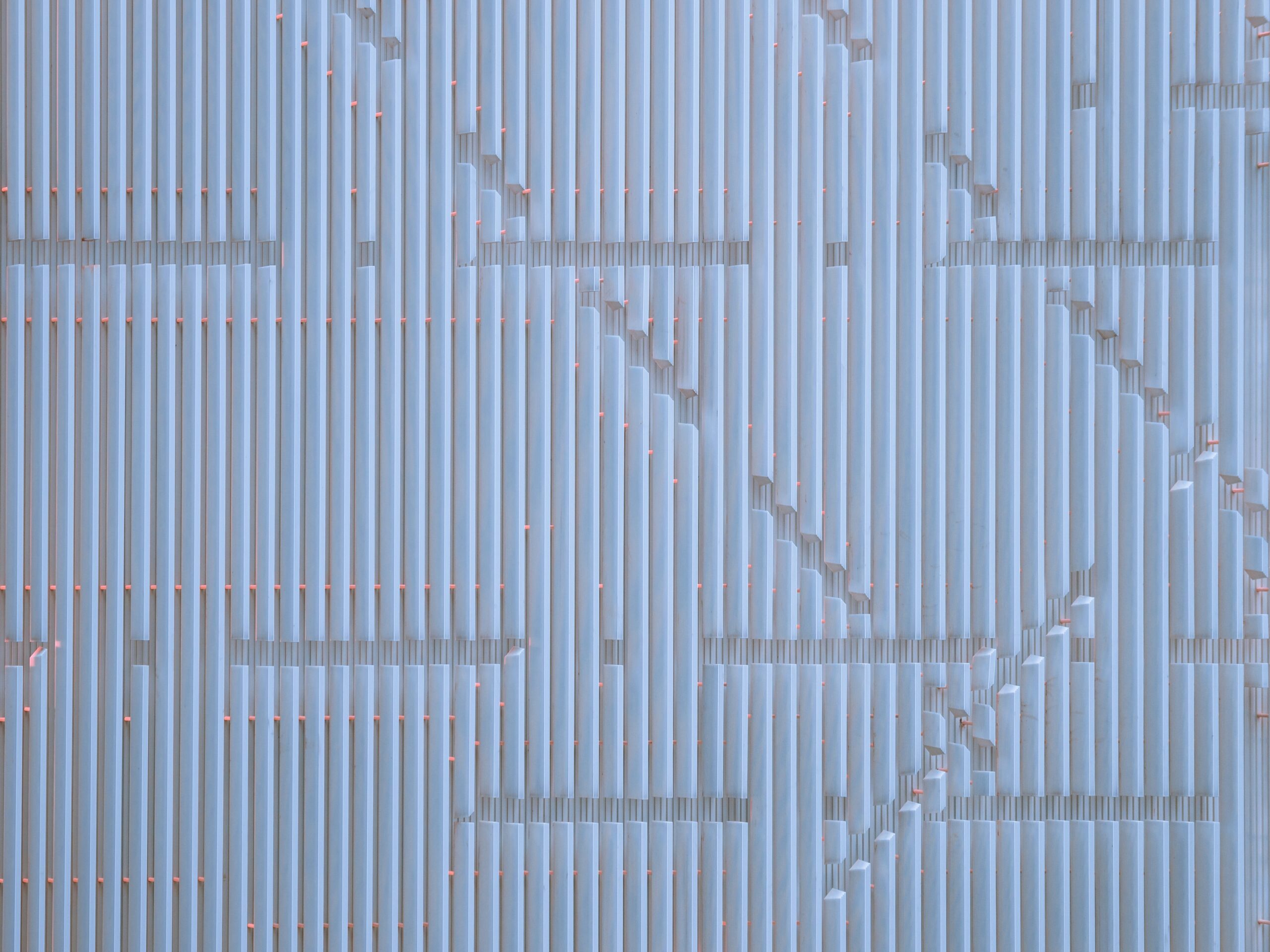 Hyper-realistic photography contrasting a small, hand-held sample piece of an aluminum sandwich panel with a large, full-sized production panel. The sample piece is on a workbench with design blueprints, while the full panel is in the background, ready for shipment. Soft, focused lighting on the sample, with the larger panel slightly blurred. Clean composition, no text, no brand logos. Illustrate the difference between prototyping and bulk orders from aluminum sandwich suppliers.