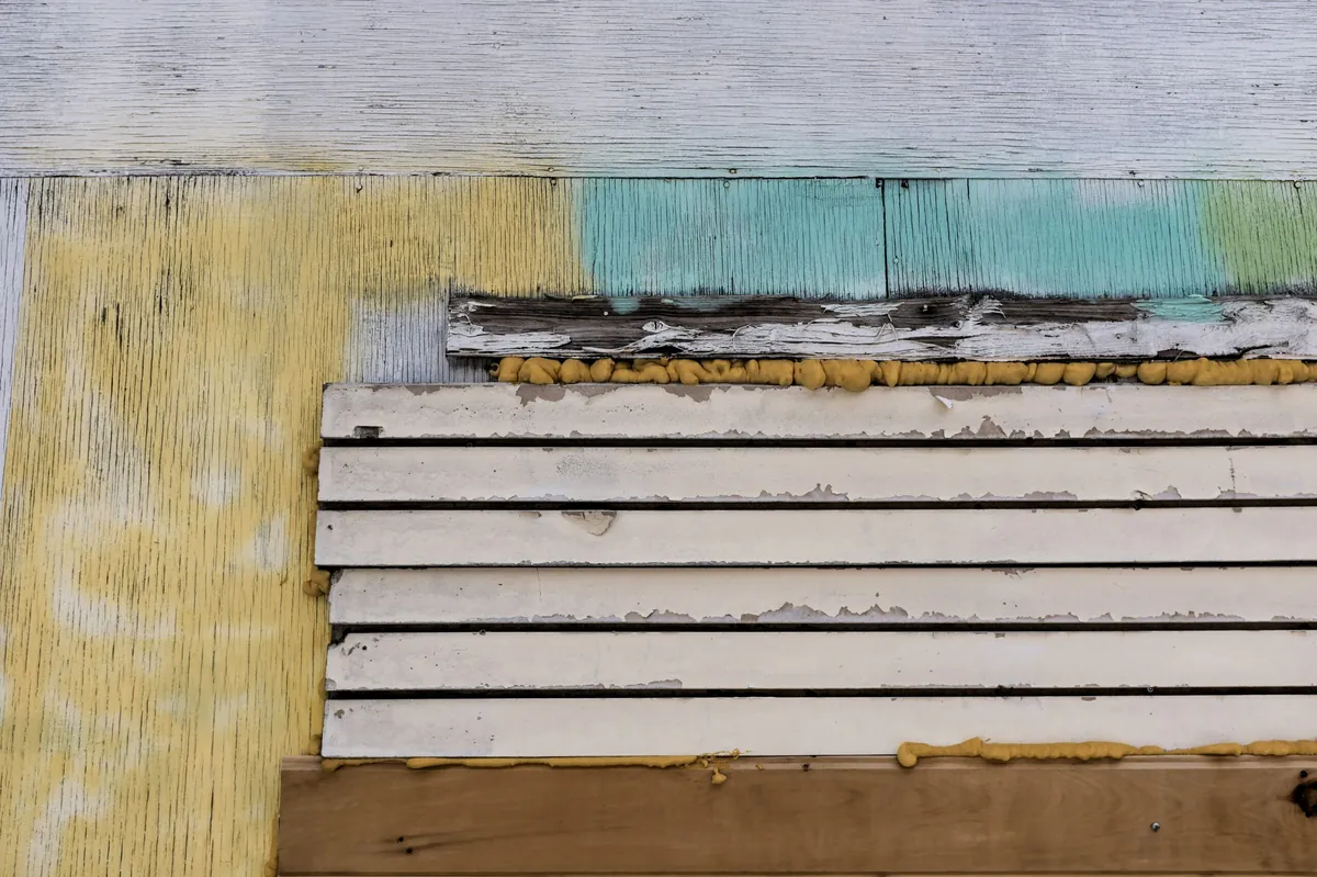 Hyper-realistic photography of a cross-section of a fire-rated agricultural panel, clearly showing layers of mineral wool or PIR core sandwiched between durable, corrosion-resistant FRP facings. The panel is installed as part of a wall in a clean, well-lit agricultural facility, with a subtle hint of farm equipment in the background. Emphasize the panel's thickness and robust construction. Soft, even lighting. No text, no brand logos, clean composition.