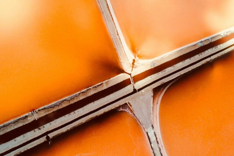 Hyper-realistic photography of a cross-section of a fire-rated composite sandwich panel, showing distinct layers of core material and facing. The panel is partially charred on one side, with flames subtly visible in the background, emphasizing its fire-resistant properties. Clean composition, no text, no brand logos.