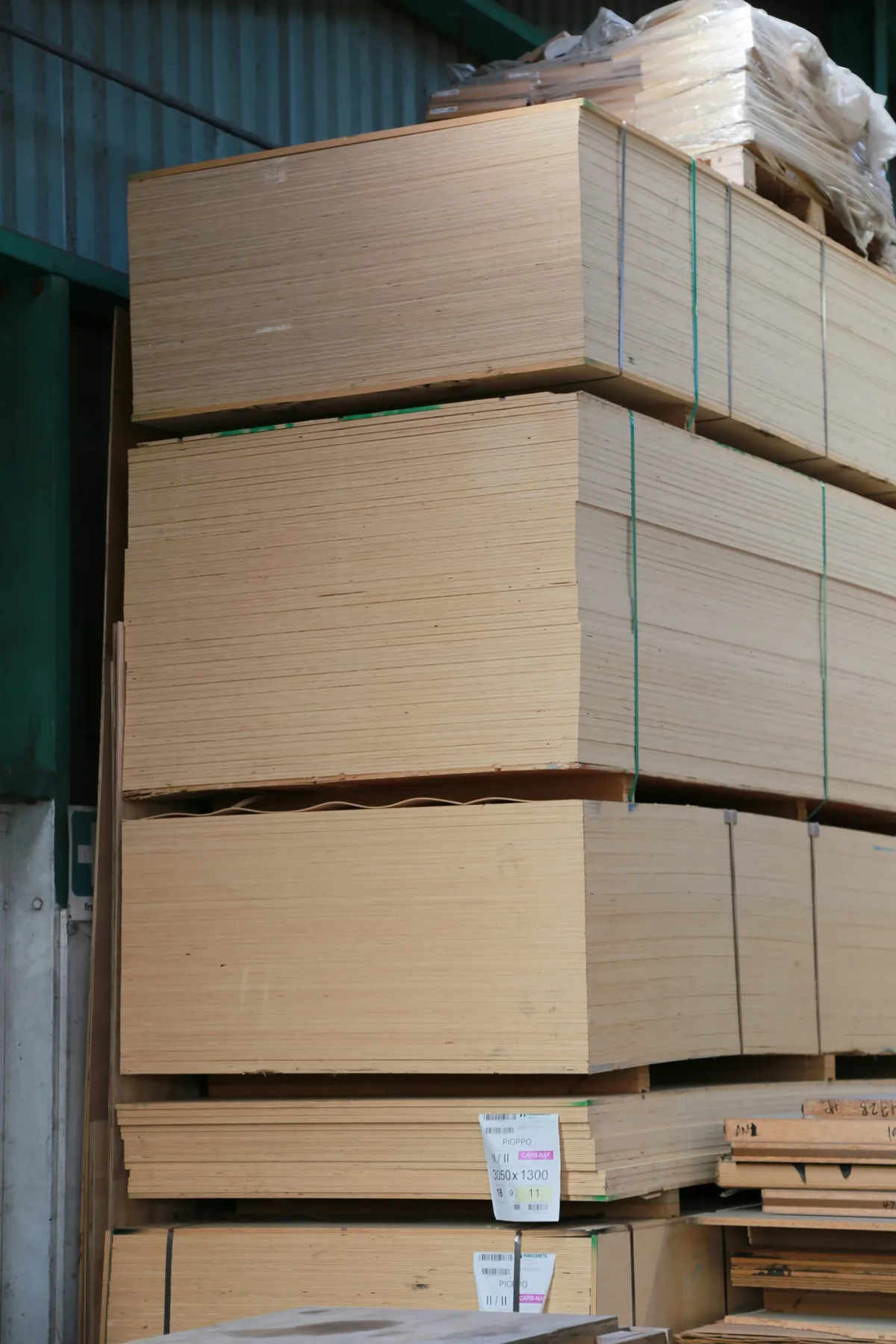 Hyper-realistic photography of a stack of aluminum sandwich panels securely packaged for international shipping. The panels are protected with corner guards, thick foam padding, and heavy-duty shrink wrap, loaded onto a wooden pallet. A forklift is visible in the background of a clean warehouse. Industrial lighting, focus on the robust packaging. Clean composition, no text, no brand logos. Showcase the care taken by aluminum sandwich suppliers in logistics.