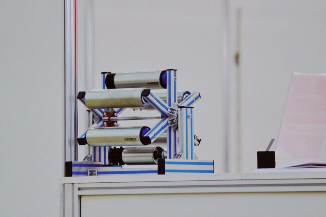 Hyperrealistic Photography Of A Stateoftheart Composite Pane Overview Hyperrealistic photography of a state-of-the-art composite panel production line in a brightly lit, clean factory. A long, continuous sheet of white FRP foam core sandwich panel moves along automated rollers under industrial lighting. The perspective is a dynamic, low-angle shot looking down the length of the production line, emphasizing scale and precision engineering. No people, no text, no brand logos, cinematic lighting.