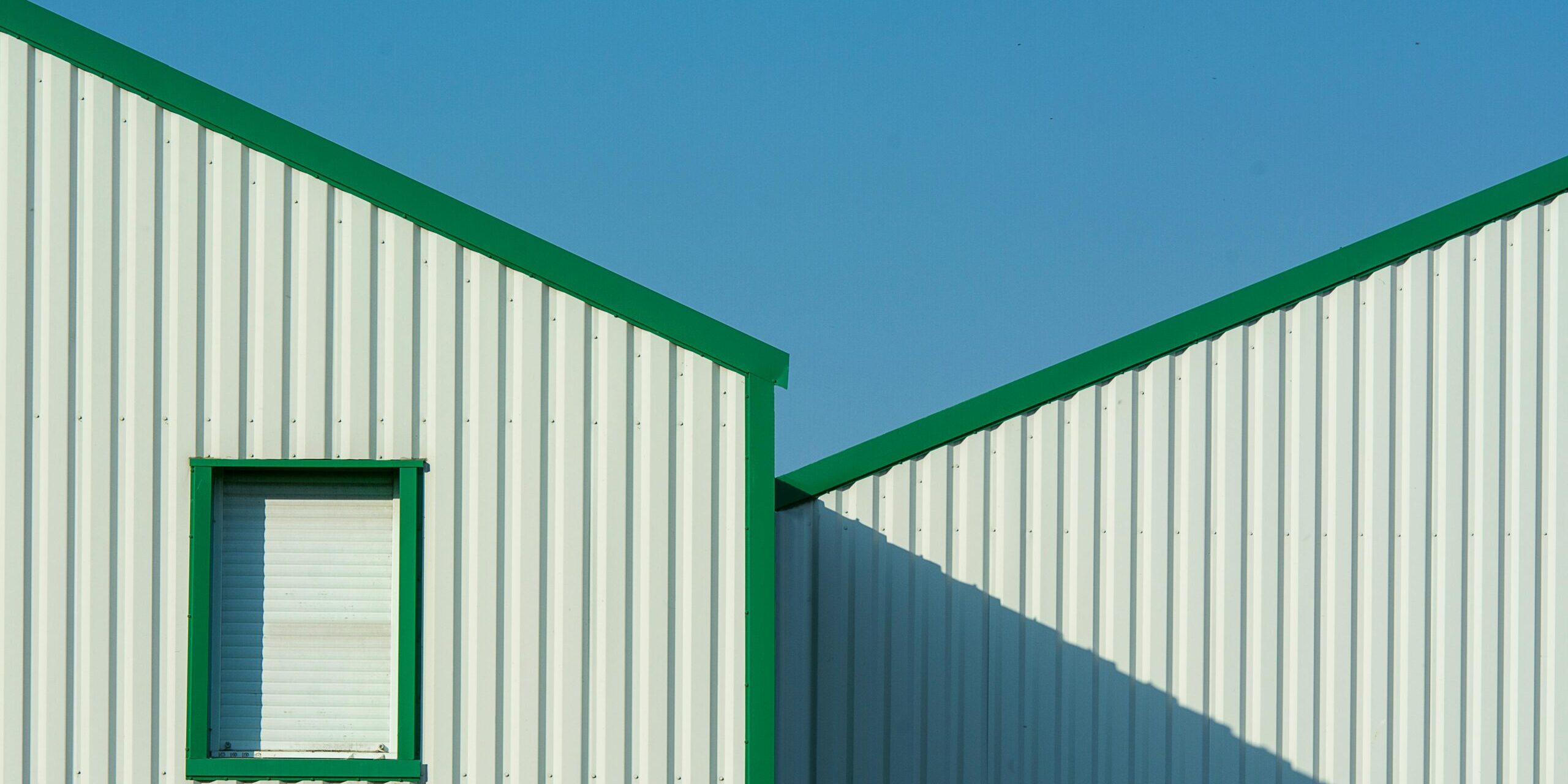 Minimalist building exterior with green accents un Minimalist building exterior with green accents under a clear blue sky.
