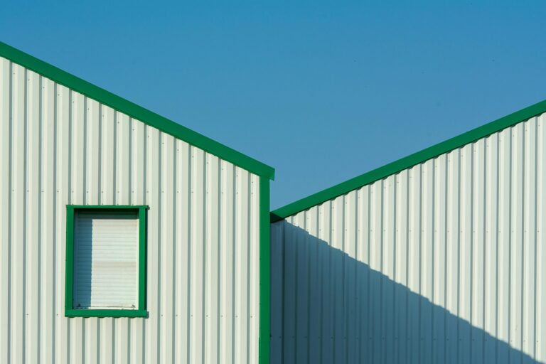 Minimalist building exterior with green accents under a clear blue sky.