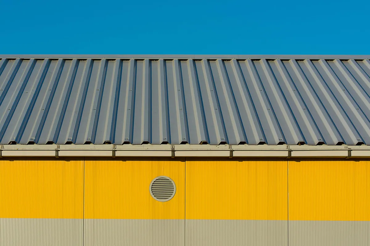 Yellow painted facade showing coated aluminium panels in sunlight