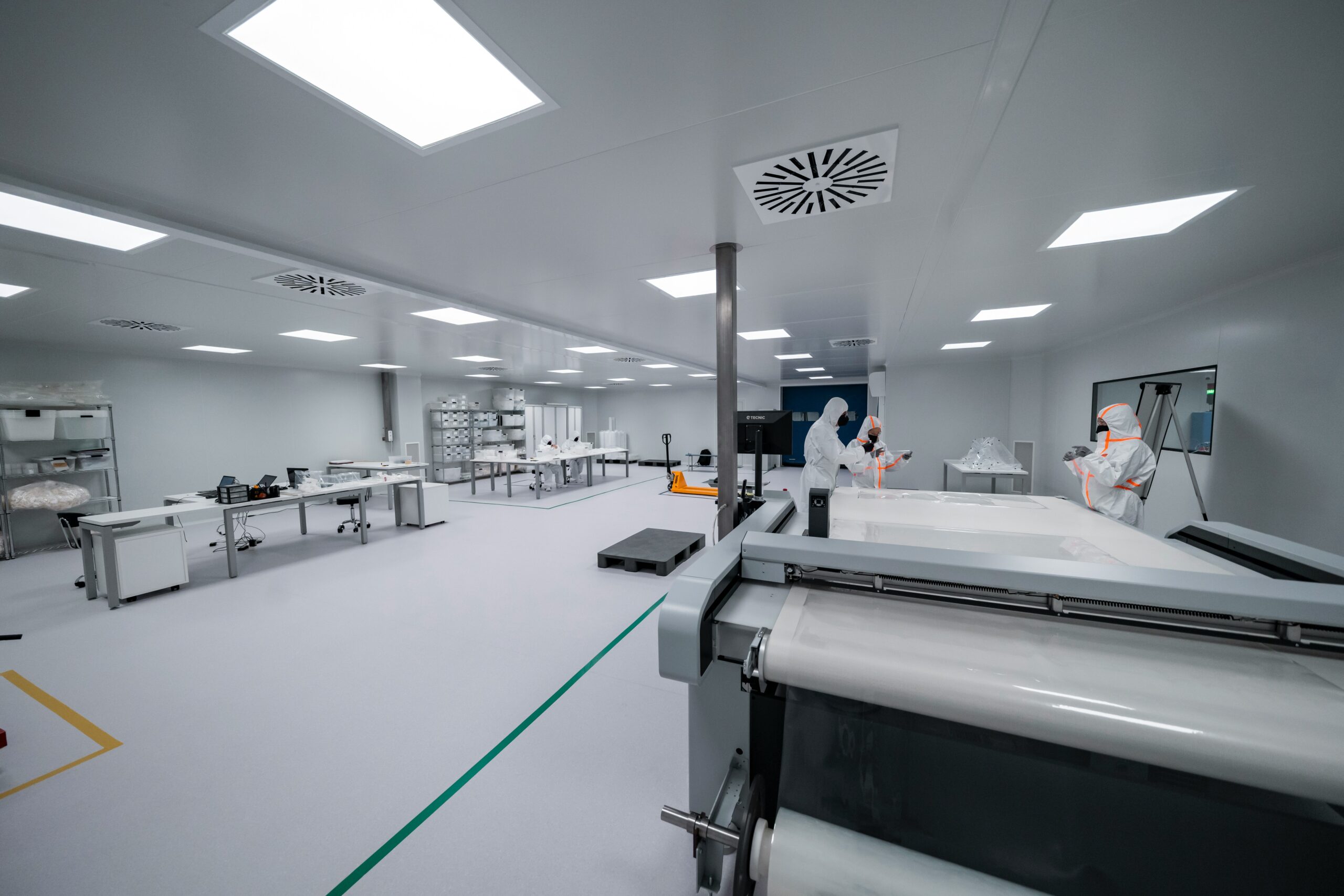 Workers are inside a clean room manufacturing something.