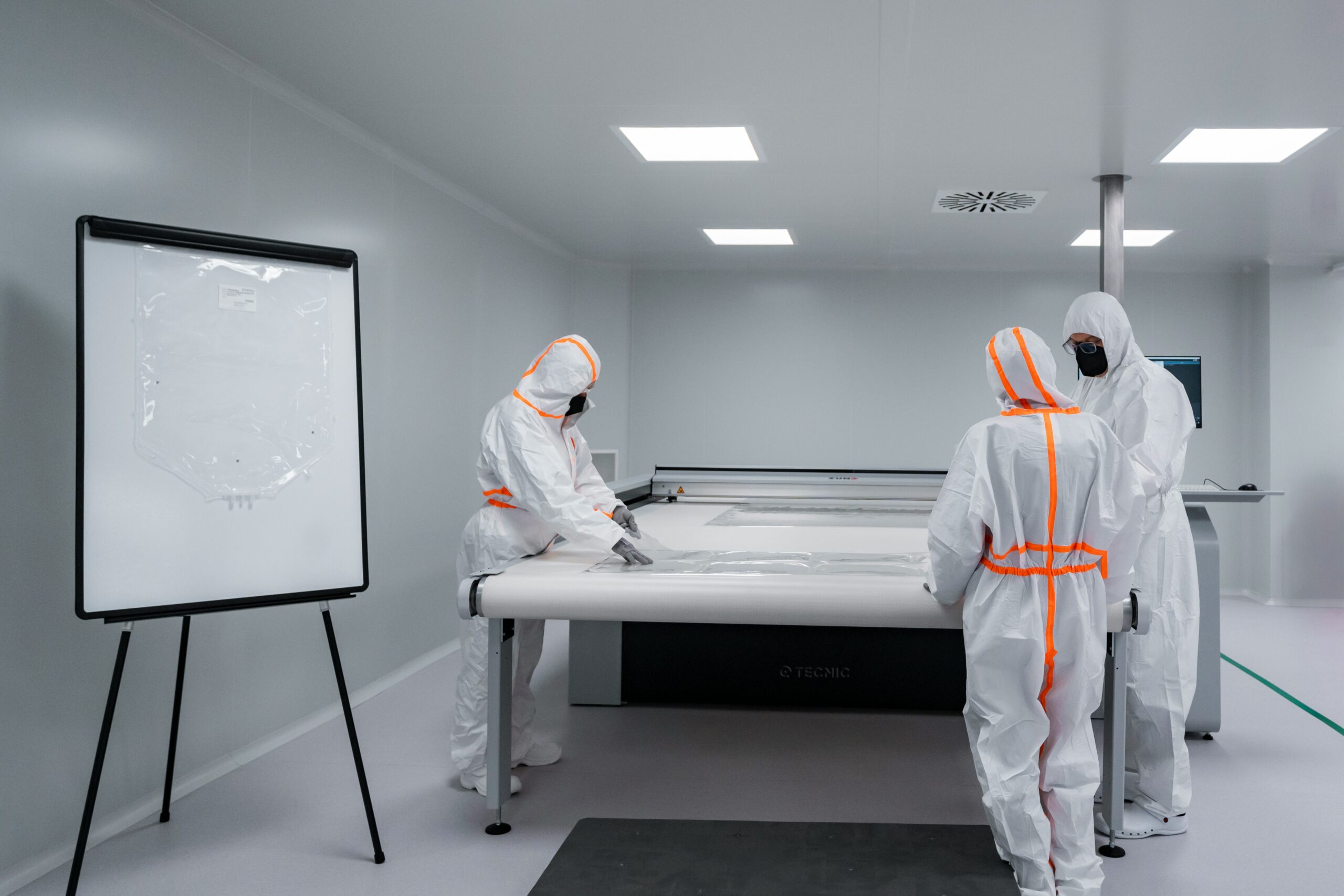 Workers in protective suits work in a cleanroom.